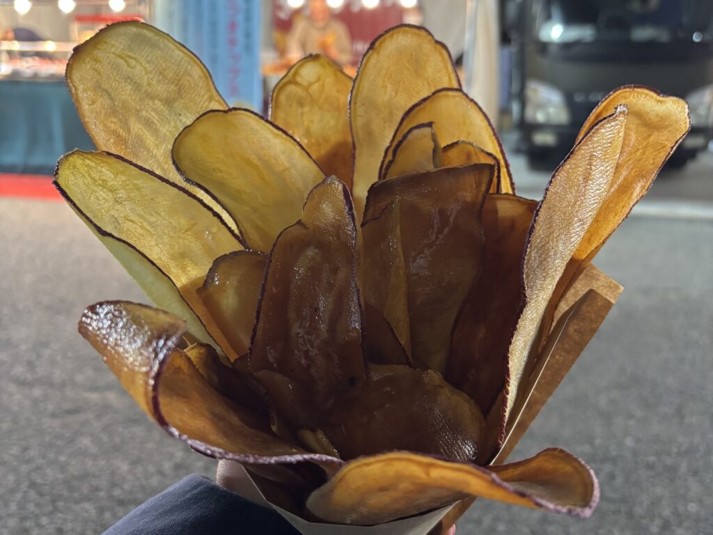 ラーメンエキスポの屋台で販売されていた、大きく薄く揚げたさつまいもチップスを手に持った写真。