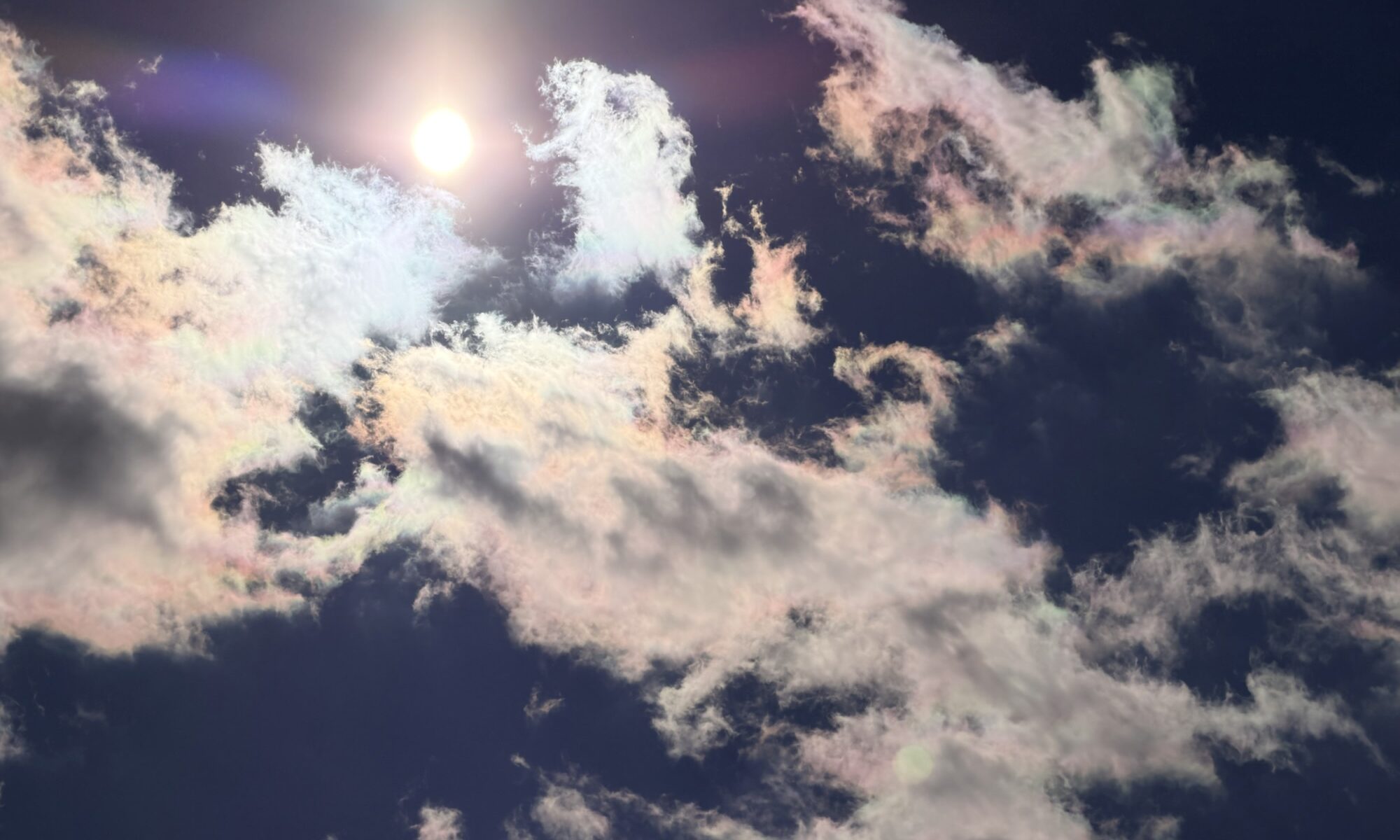 空にうっすらと虹色に染まった彩雲の写真