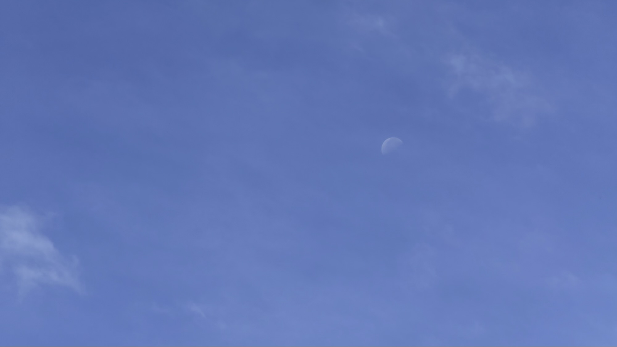 6月の青空に薄い雲と昼間の月が浮かぶ月曜日の朝