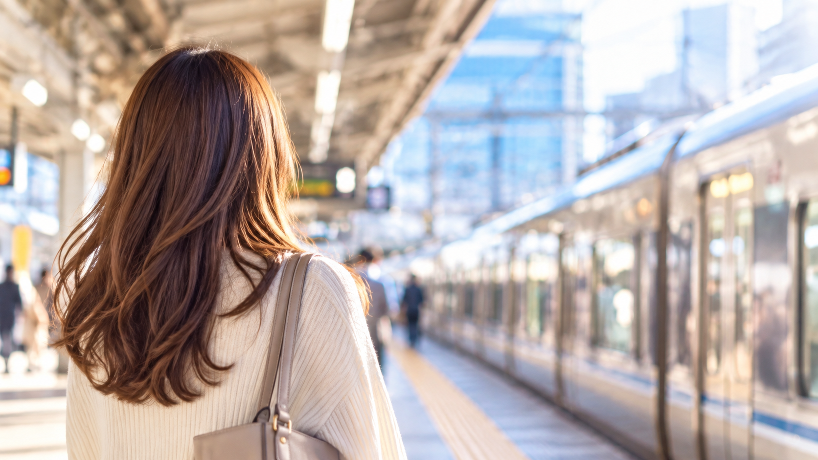 朝の駅で電車に乗っておでかけする女性の後ろ姿